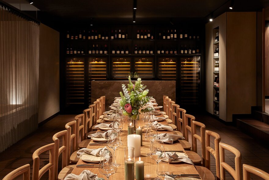 A long table set for a private dinner in a dimly lit restaurant. 