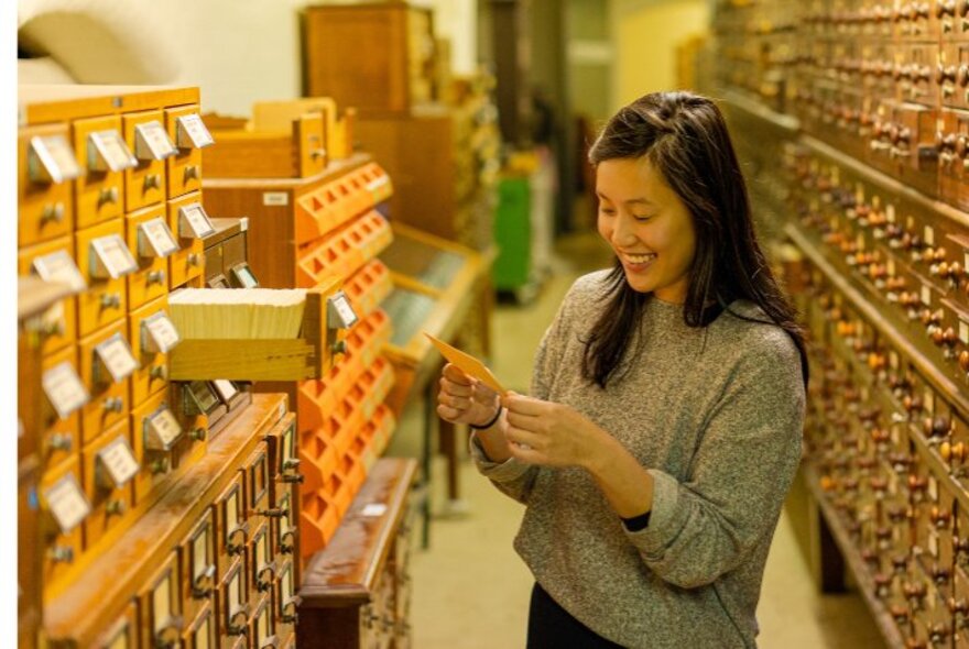 A visitor exploring the historic, behind-the-scenes card catalogue collection during a guided tour at the State Library Victoria in Melbourne.