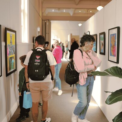 People in a corridor viewing artwork the walls. 