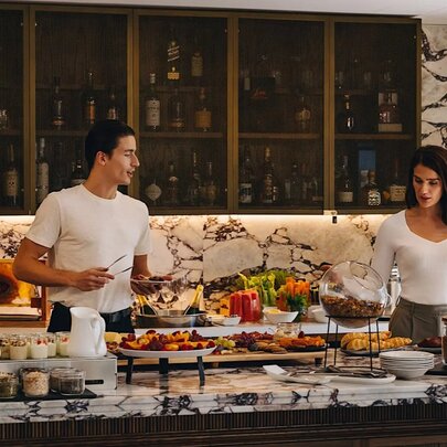 A couple selecting food from a buffet spread at Elevate Club Lounge located in the Pullman Melbourne City Centre.