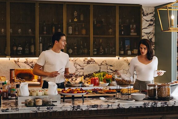 A couple selecting food from a buffet spread at Elevate Club Lounge located in the Pullman Melbourne City Centre.