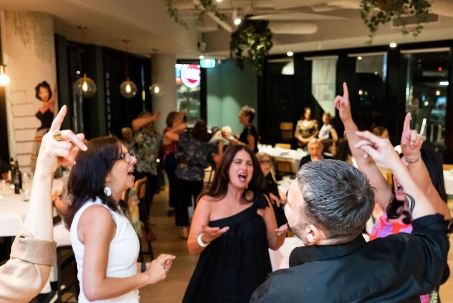Patrons dancing and celebrating at a restaurant with live music.