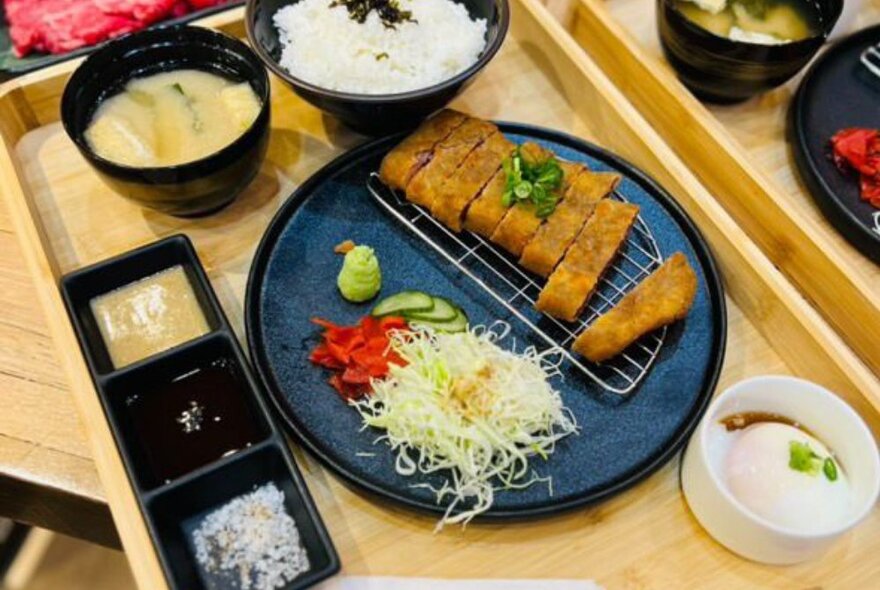 A plate of Japanese food including fried pork, pickled vegetables, condiments and rice.