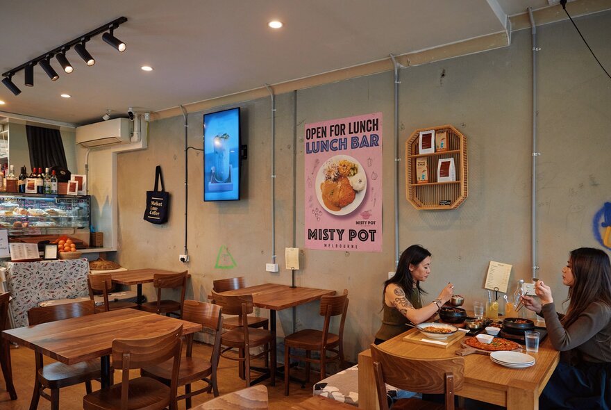 Two friends are eating Korean food inside a Korean restaurant. 