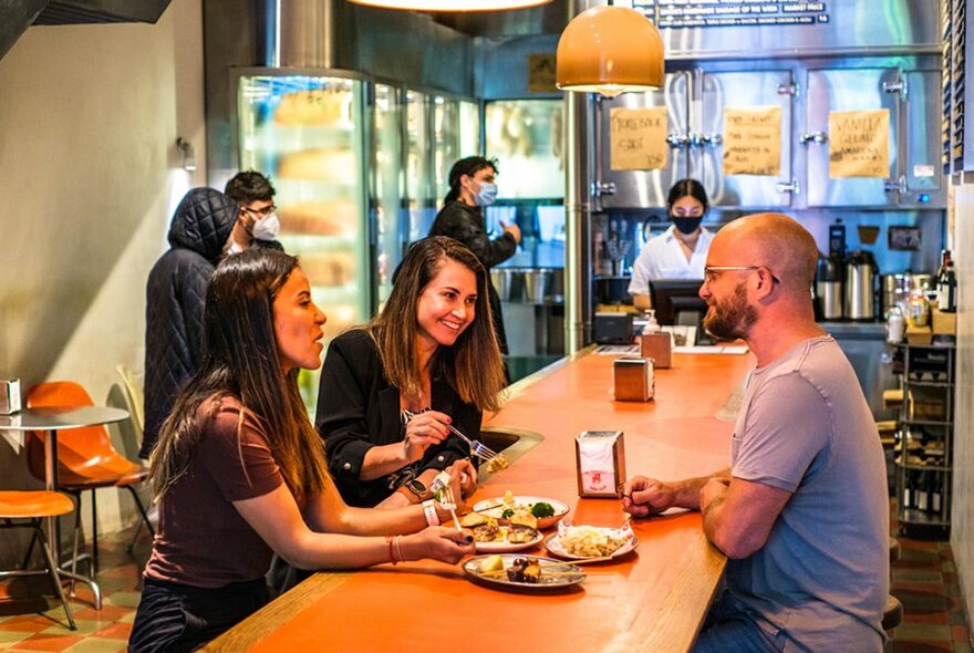 People dining at a long orange table in a diner.