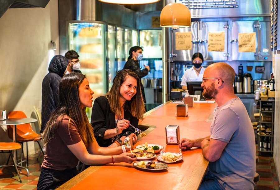 People dining at a long orange table in a diner.