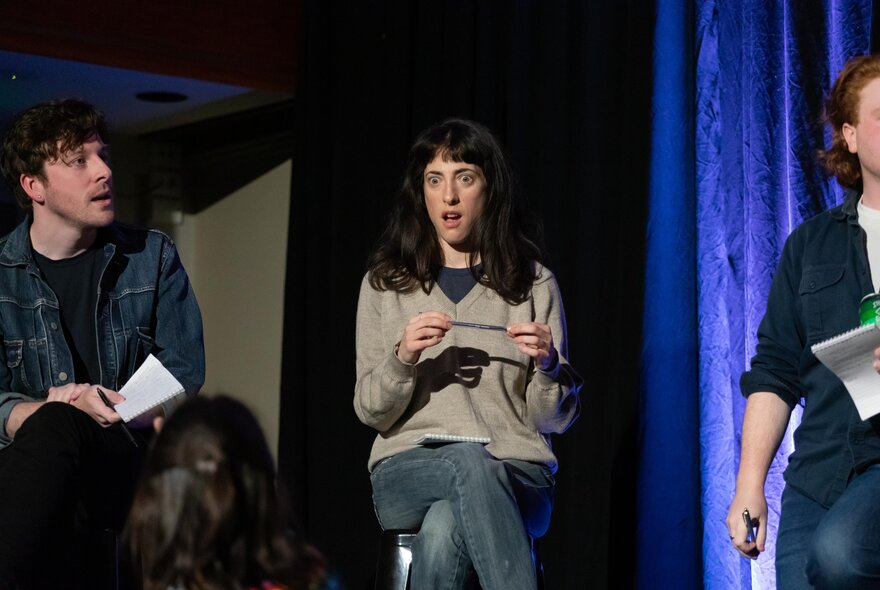 Improv comedians on stage performing in front of an audience in a role playing game.
