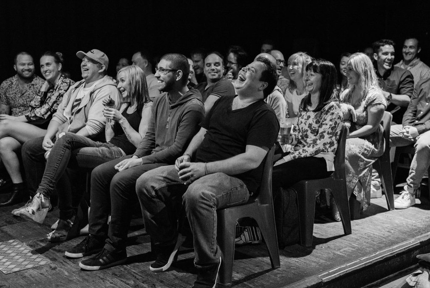 Four rows of people sitting smiling and laughing.