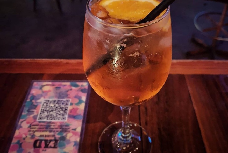 Aperol Spritz on bench next to a FAD QR sign in.