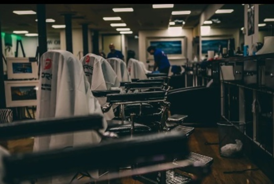 Rows of barber seats with towels under overhead lights.