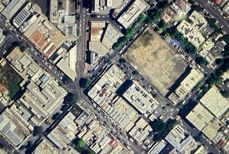 Aerial photo of a city with streets meeting at a crossroad and buildings.
