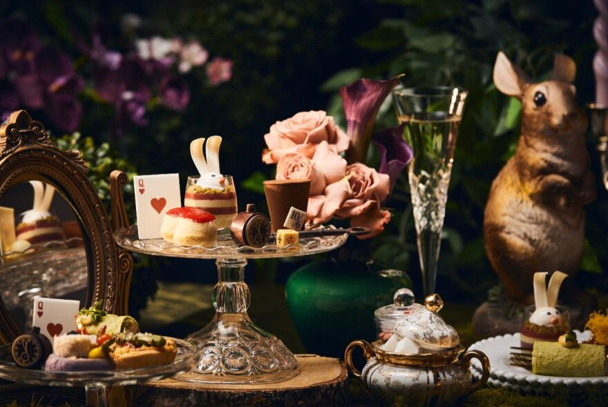 Alice in Wonderland-inspired afternoon tea setting with rabbit cakes on cake stands and plates.