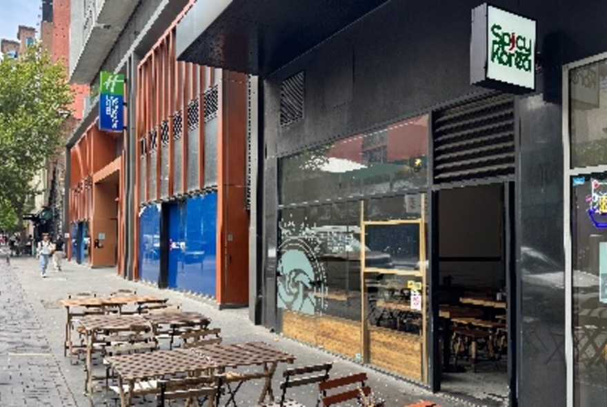 The exterior of Spicy Korea restaurant with empty tables on the pavement. 