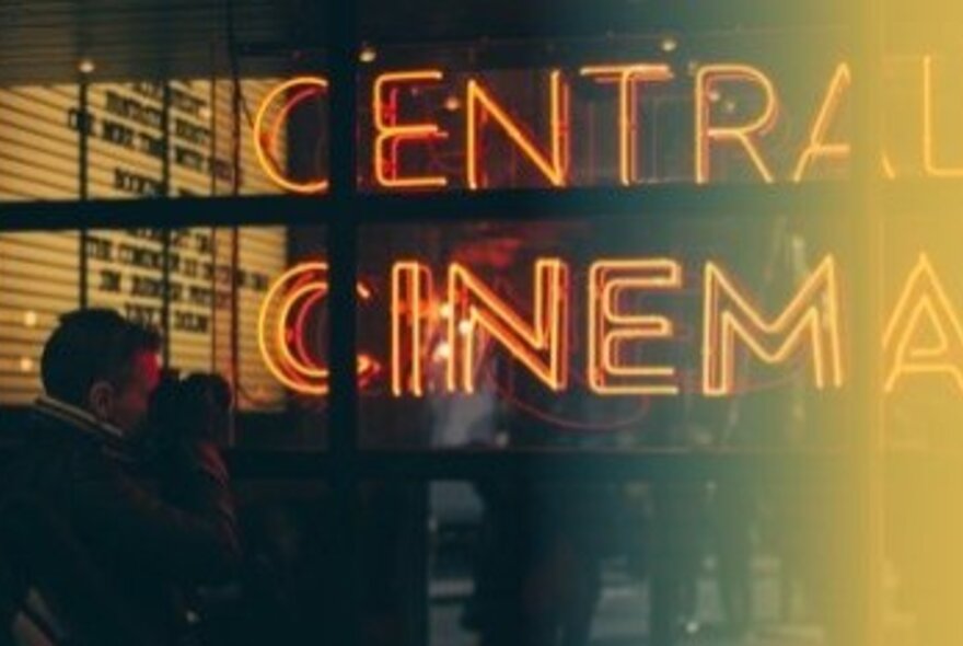 A large window with red neon signage displaying the words CENTRAL CINEMA, with people milling around outside the cinema and in the background.