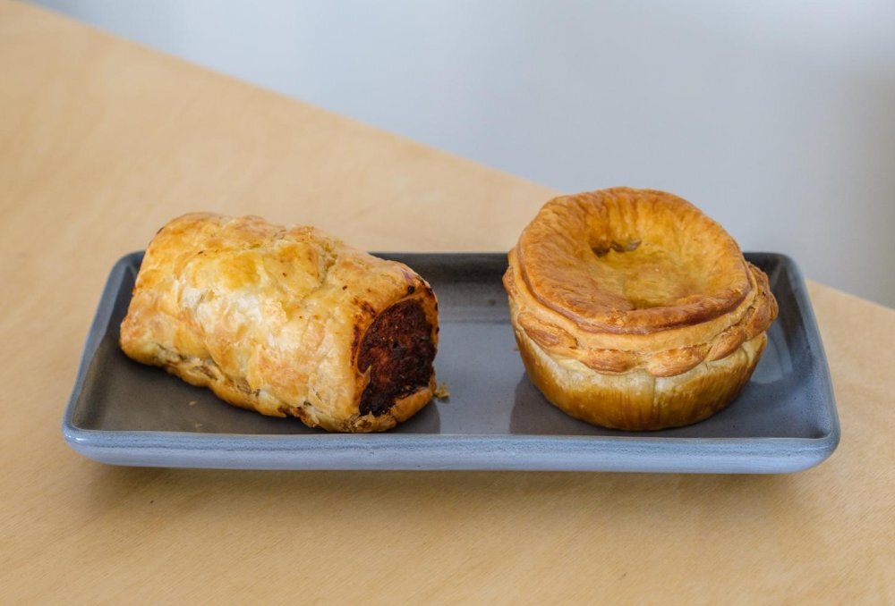 Pie and sausage roll on a blue plate.