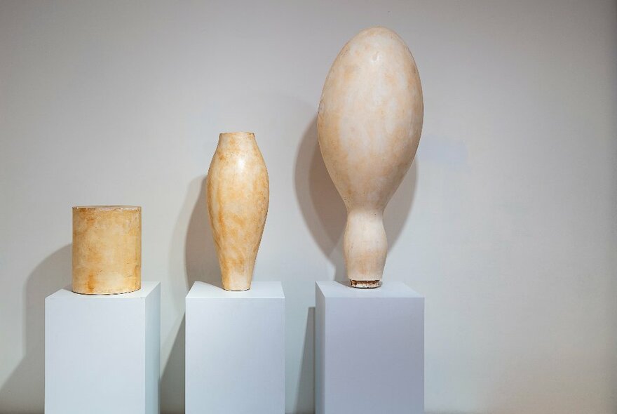 Examples of Hans Arp sculptures presented on white pedestals in a gallery setting.