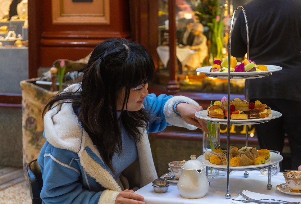 A woman is choosing a cake from a cake stand.