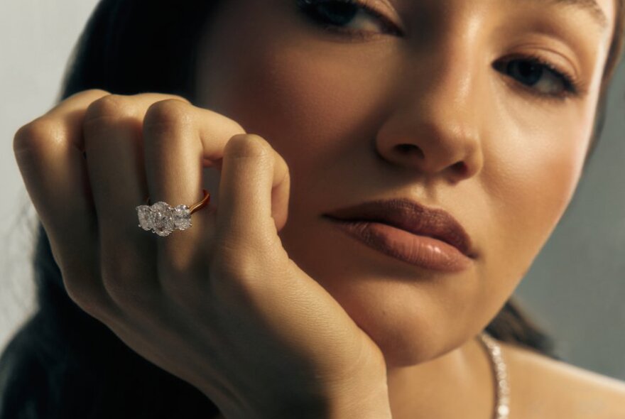 A model wearing an engagement ring with three giant diamonds 