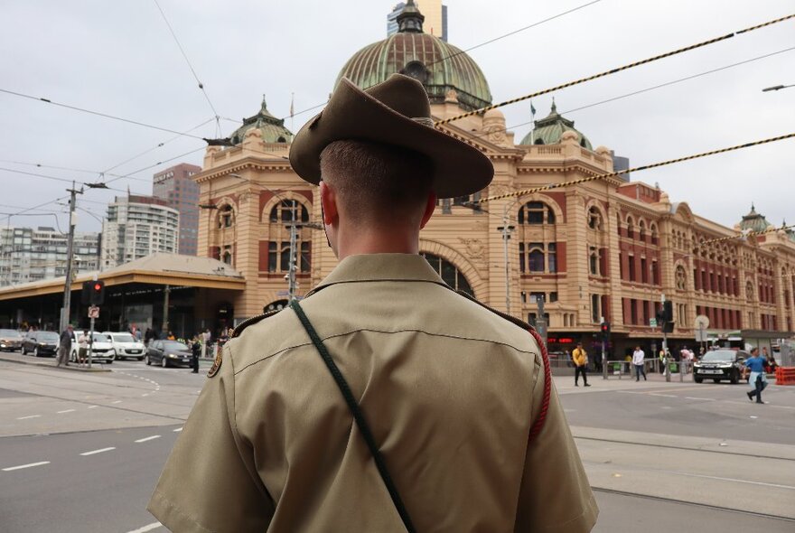 The back of a man in Australian Army uniform facing Flinders Street Station.