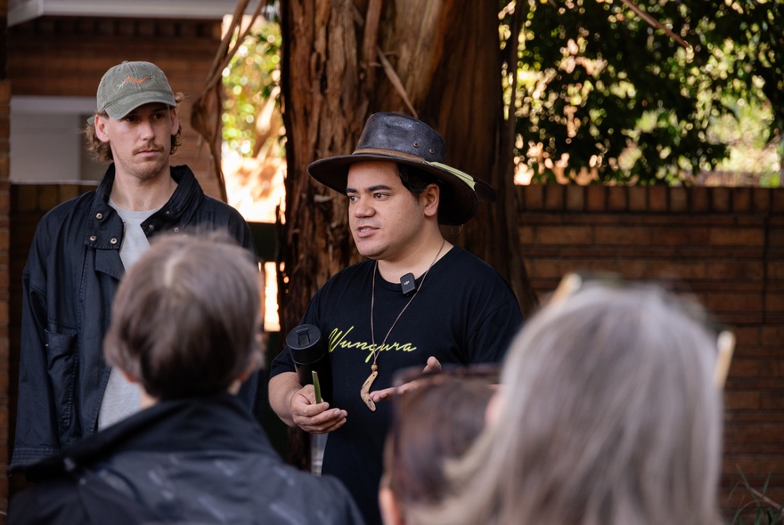 People listening to a speaker in an outdoor setting.