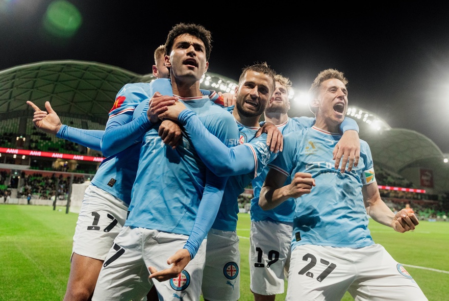 A mens soccer team in pale blue kit standing in a group during a game.