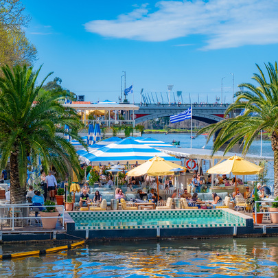 A floating bar with a pool and palm trees, on the river in the city on a sunny day.