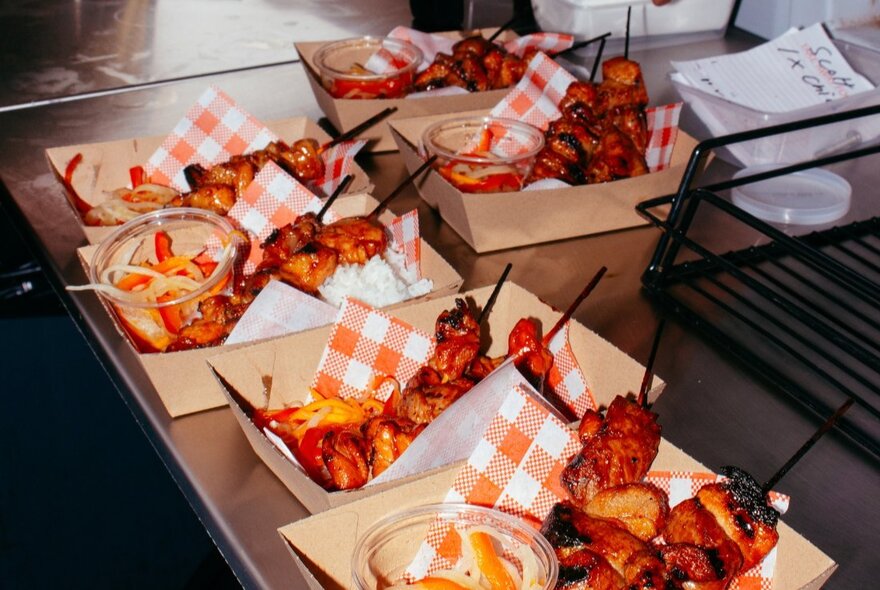 Boxes of fried food with sauce and check serviettes.