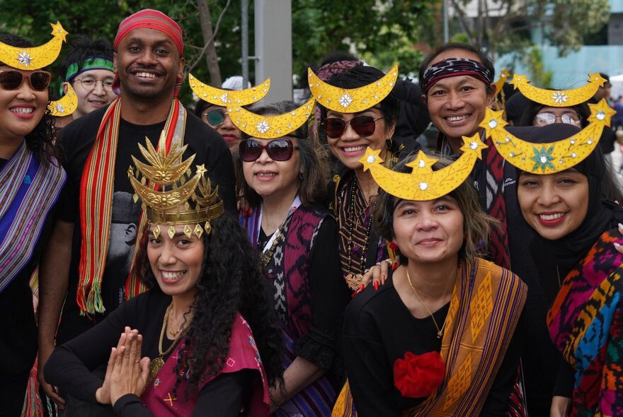 A group of Indonesian people in traditional dress, each wearing headbands with yellow moon-shapes on their foreheads.