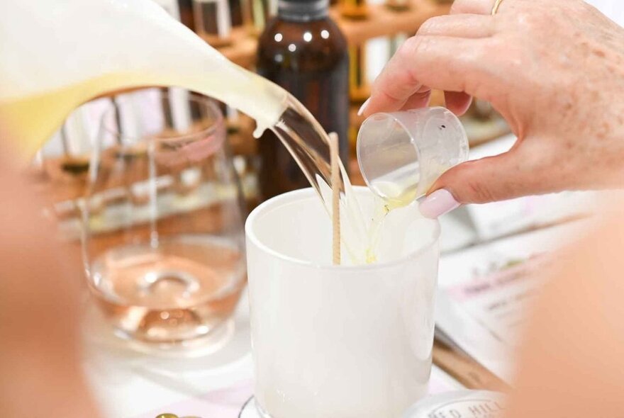A candle-making workshop with a participant blending ingredients to create custom scented candle.