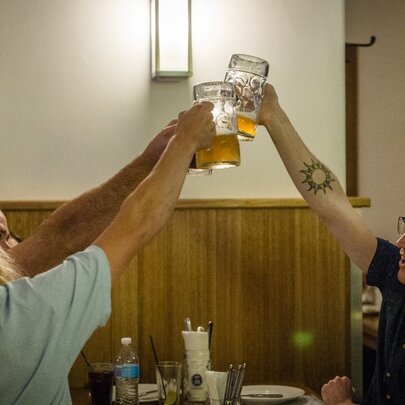 Three people raising beer steins to say cheers