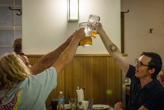 Three people raising beer steins to say cheers