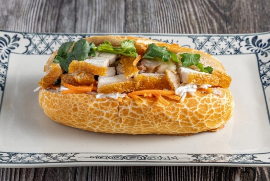 A banh mi, a crusty bread roll filled with crispy roast pork pieces, fresh salad and coriander.