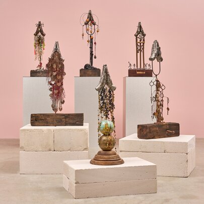 Display of totemic sculptural pieces on plinths in a gallery setting.