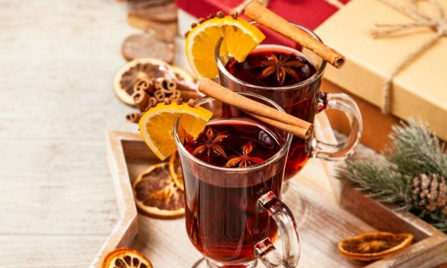 Mulled wine surrounded by decorations on a wood table