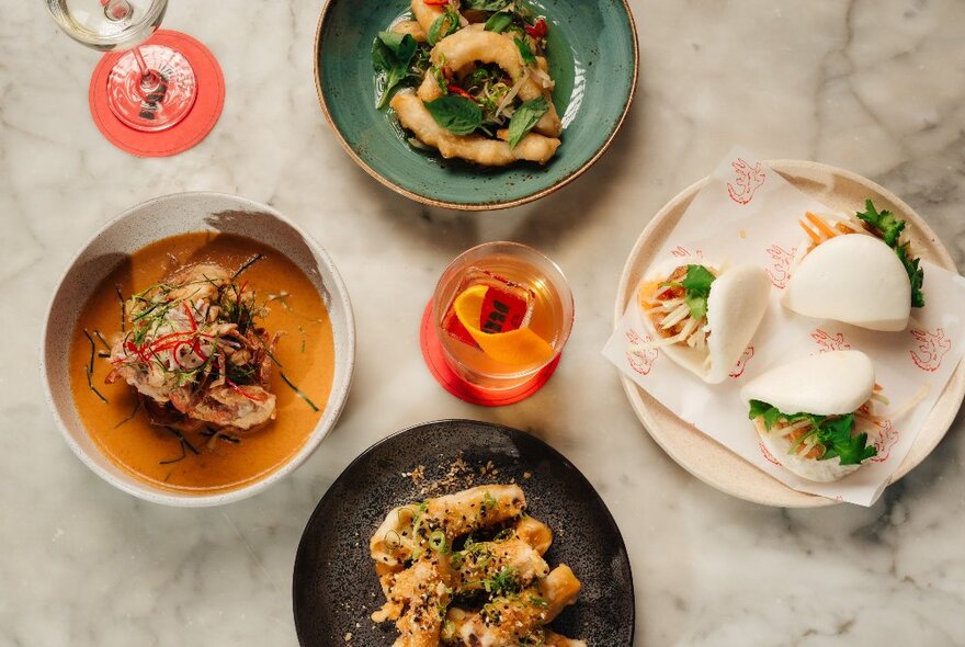 A selection of South East Asian dishes presented on a marble table, seen from above.