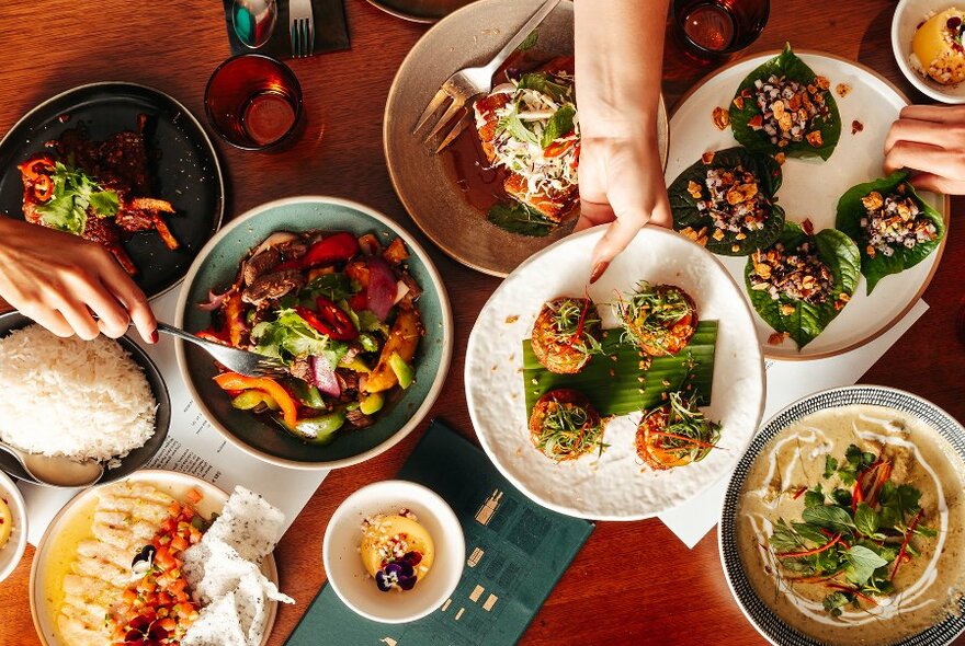 People reaching for Asian share dishes in a restaurant. 