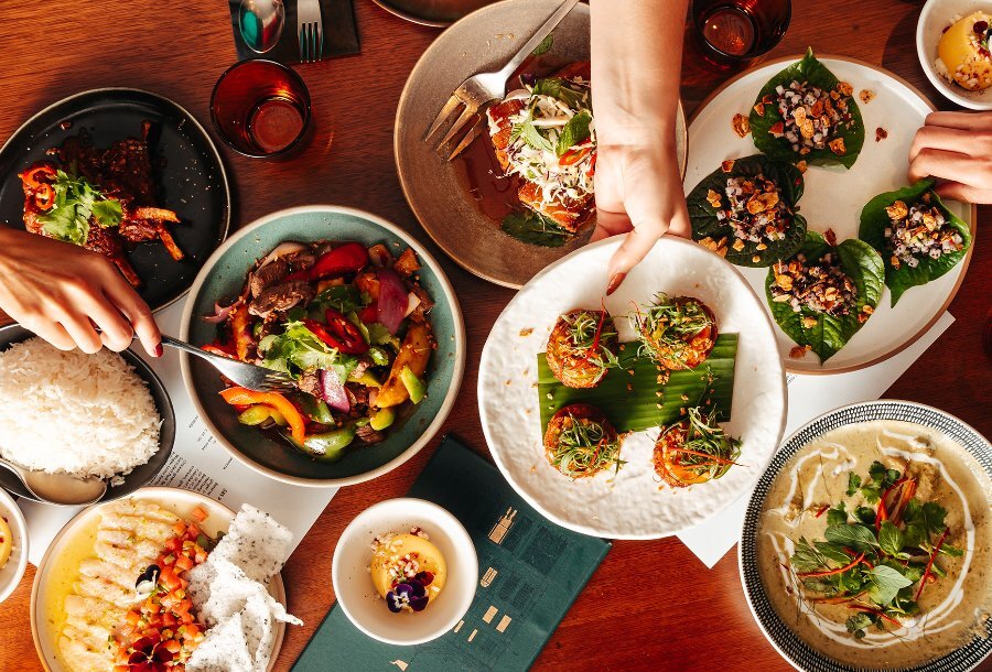 People reaching for Asian share dishes in a restaurant. 