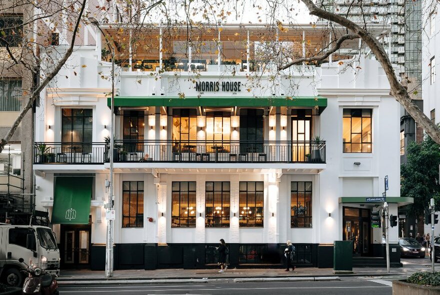 Exterior of Morris House, a white three-level building on a city corner, with balcony seating and glassed-in top floor.