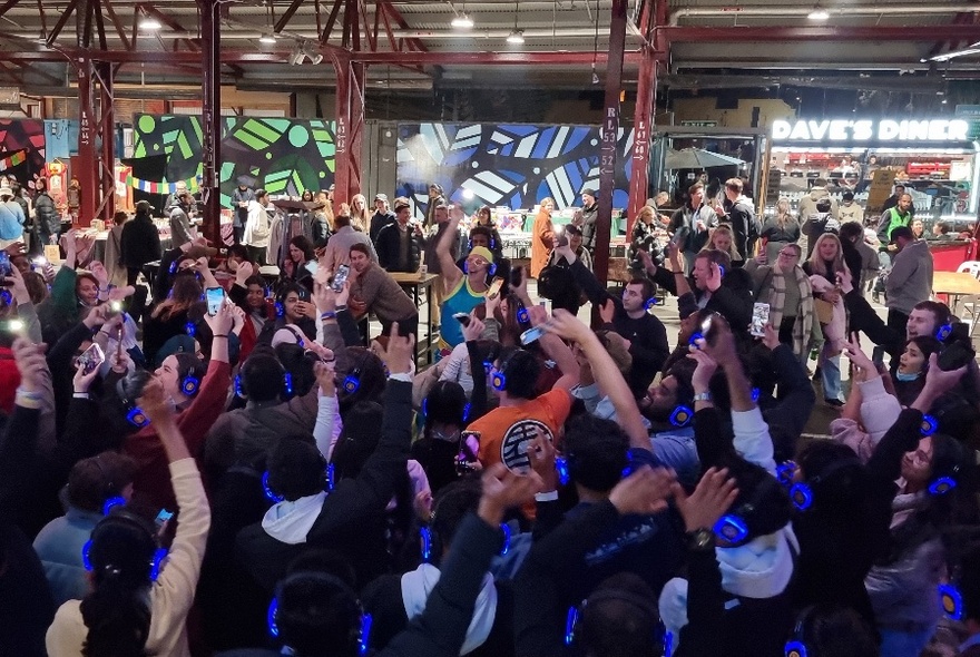 A large group of people waving their arms in the air at Queen Victoria Market.