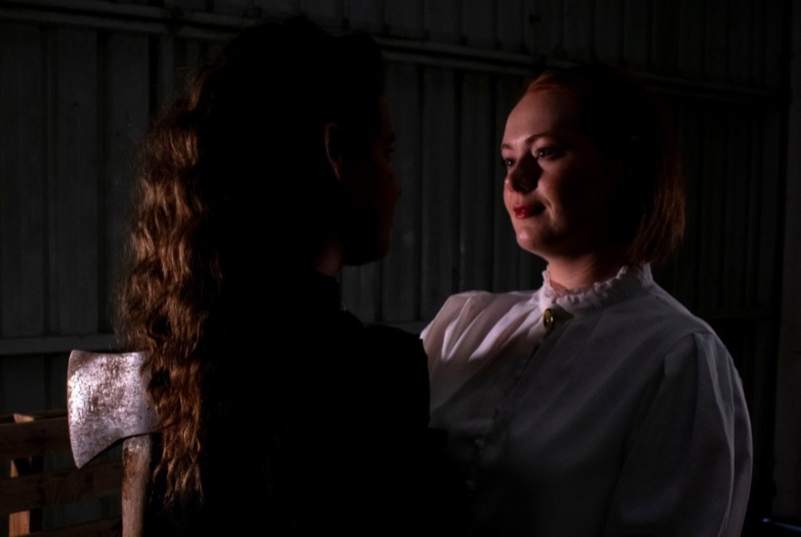 Actor dressed in 19th-century dress, posing with an axe.