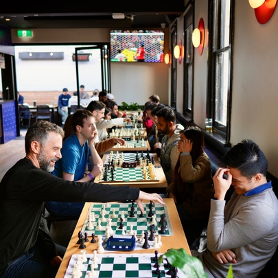 A social chess gathering where people are playing chess matches in an indoor setting of a bar.