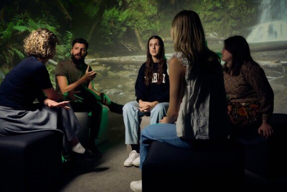 Young people sitting inside a room at Melbourne Museum, having a conversation.