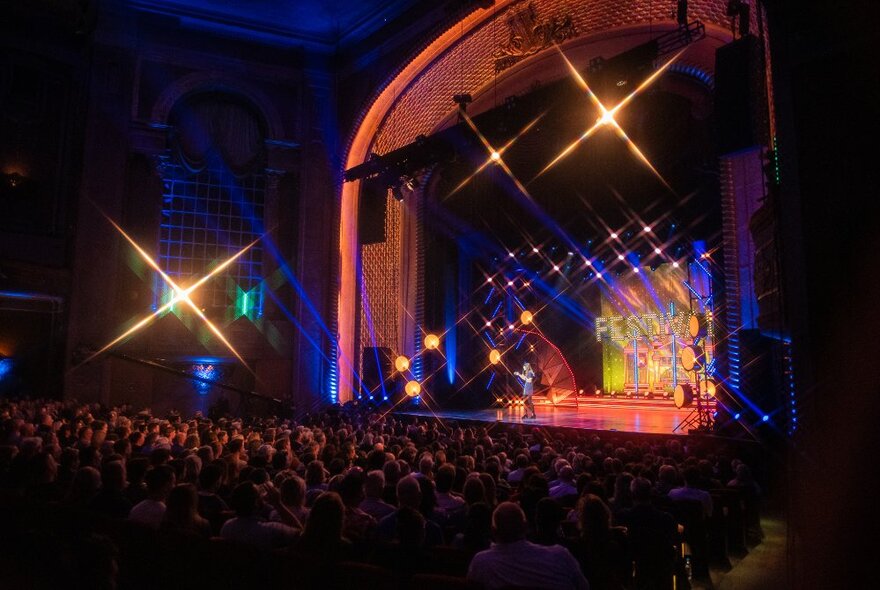 A seated theatre audience watching a performance on a stage.