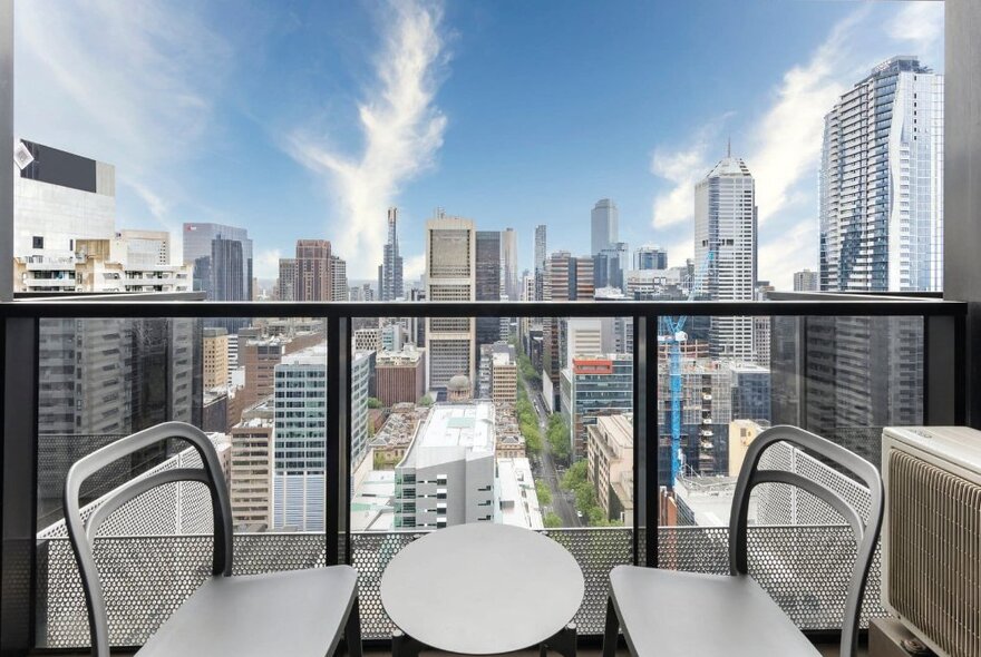 A table and chairs on a balcony overlooking the city.