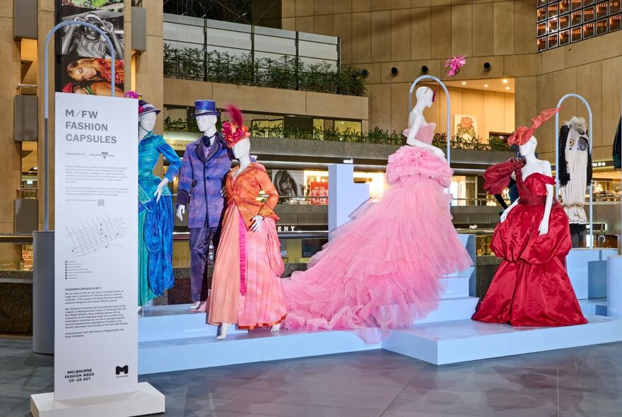 A fashion exhibit in a shopping centre with mannequins in gowns. 