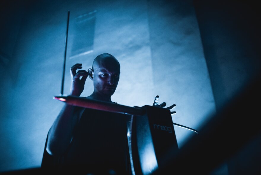 Miles Brown playing the theremin in a darkened performance space.