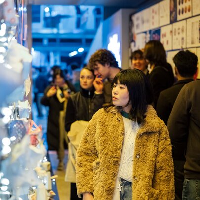 Yound adults walking through an exhibition with bright lights on one side.