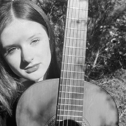 Black and white portrait of Australian classical guitarist, Ruby Cheyne, and her acoustic guitar.