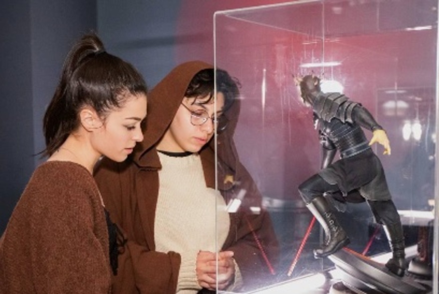 Two people looking at a glass class with a Star Wars figurine at an exhibition. 