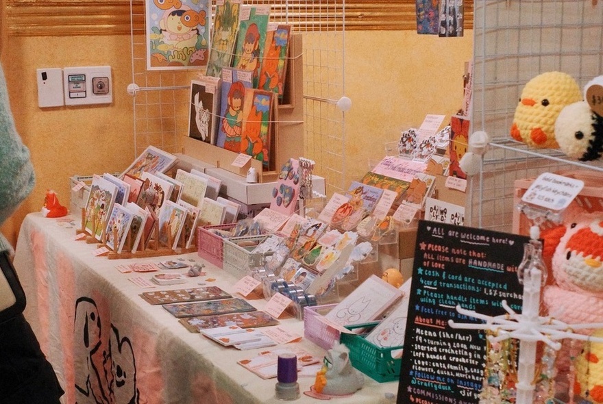 A market stall at an undercover art and stationery market, showing small items for sale.